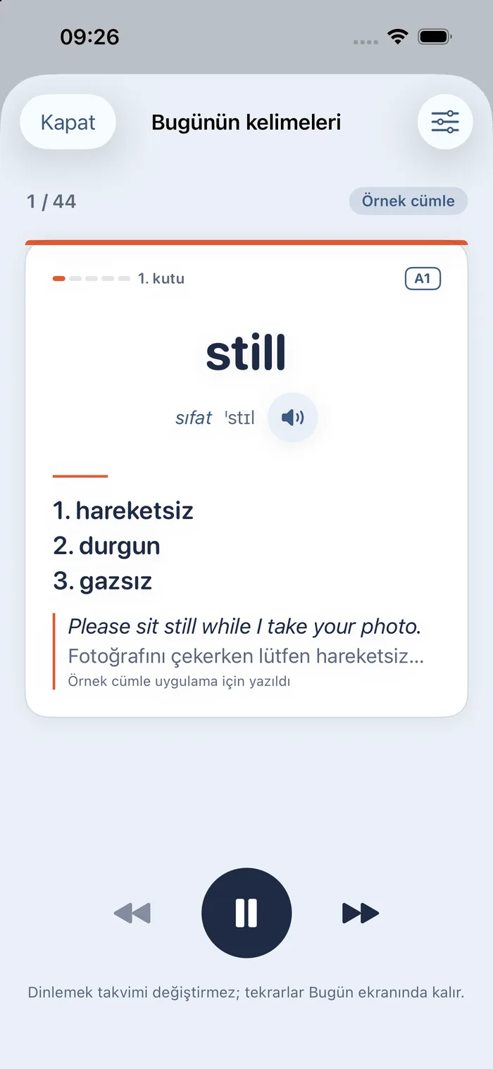 Sesli tekrar ekranı “Bugünün kelimeleri”: 1/44, Örnek cümle rozeti; still kartı açık (sıfat, okunuşu, anlamları hareketsiz, durgun, gazsız; örnek cümle Please sit still while I take your photo.); altta geri, duraklat ve ileri düğmeleri; not: Dinlemek takvimi değiştirmez; tekrarlar Bugün ekranında kalır.